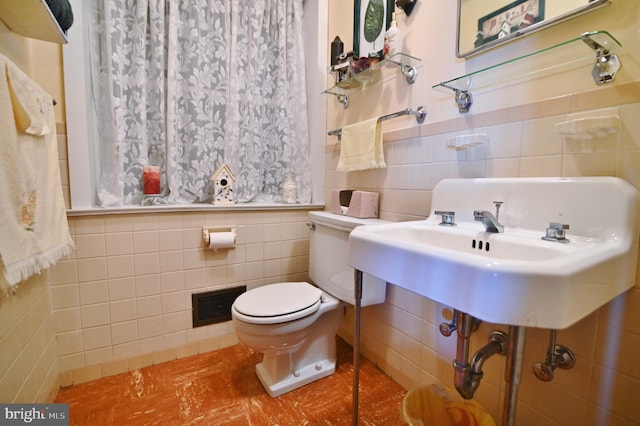 bathroom with visible vents, toilet, tile walls, and a sink