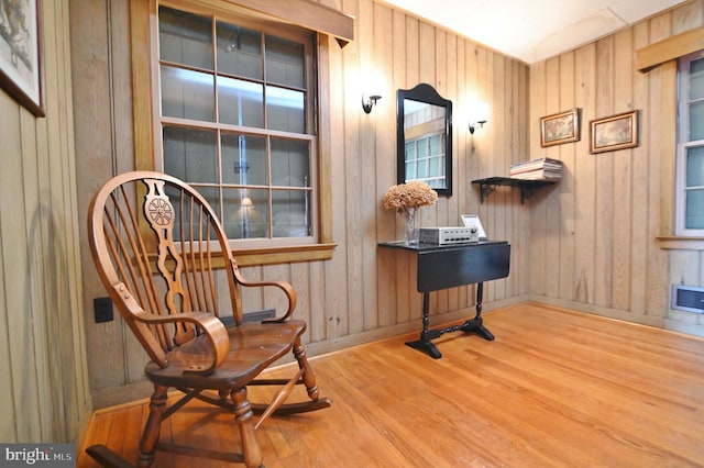 living area with visible vents, wooden walls, and wood finished floors