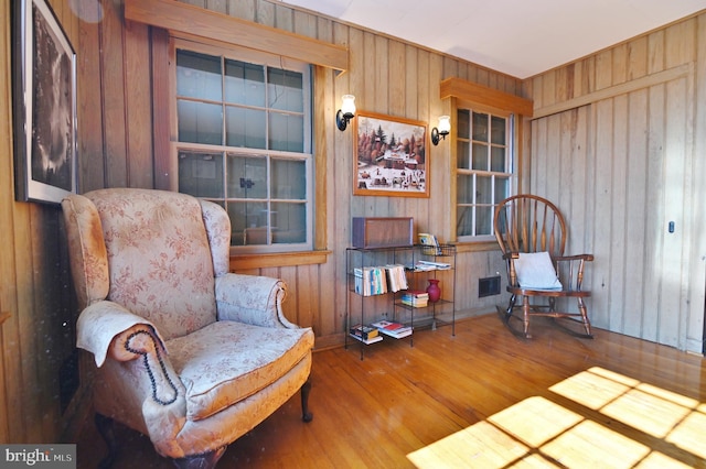 sitting room featuring visible vents, wood finished floors, and wood walls