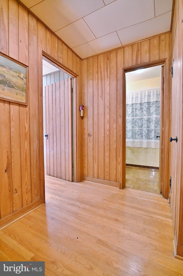 corridor with wood finished floors and wood walls