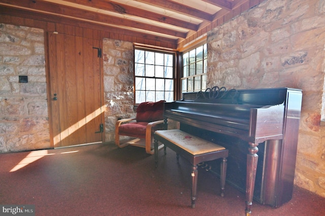 living area with beam ceiling, wooden walls, and carpet