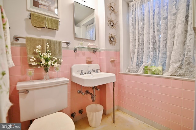 bathroom featuring a wainscoted wall, toilet, and tile walls