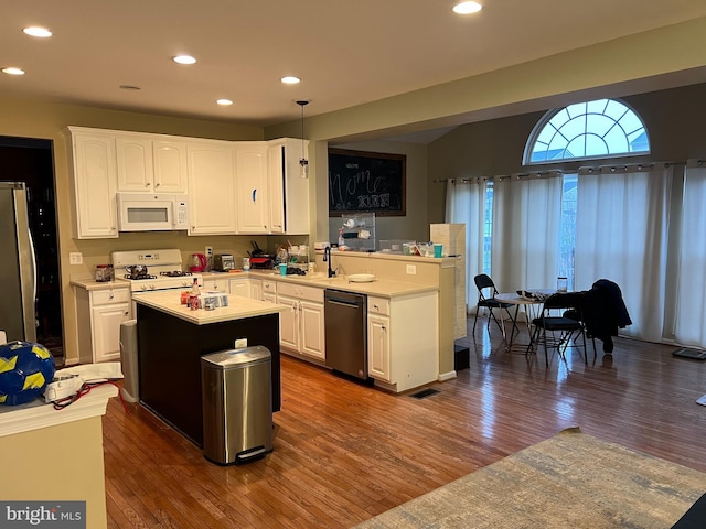 kitchen featuring pendant lighting, white appliances, white cabinets, dark hardwood / wood-style flooring, and kitchen peninsula