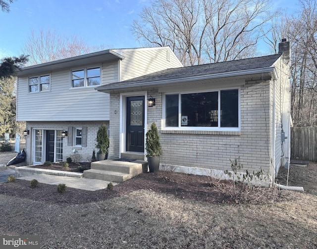 tri-level home featuring brick siding and a chimney