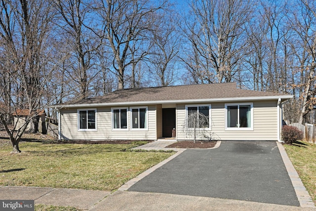 ranch-style house featuring aphalt driveway, fence, a shingled roof, and a front lawn