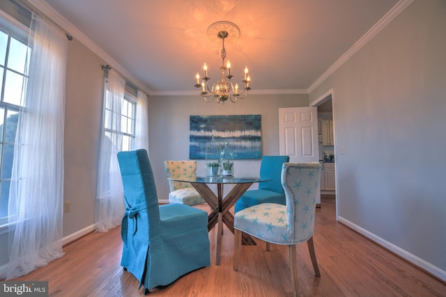 dining room featuring a notable chandelier, crown molding, baseboards, and wood finished floors