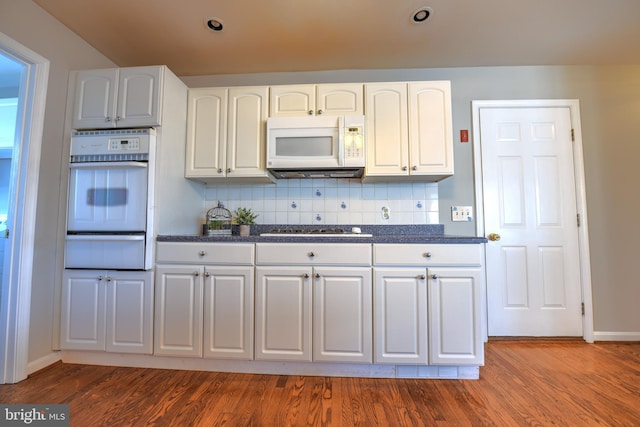 kitchen with white microwave, gas cooktop, wood finished floors, backsplash, and a warming drawer