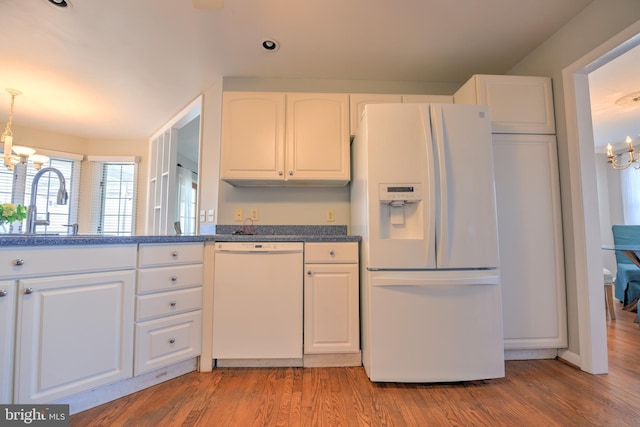 kitchen with white appliances, white cabinets, and an inviting chandelier