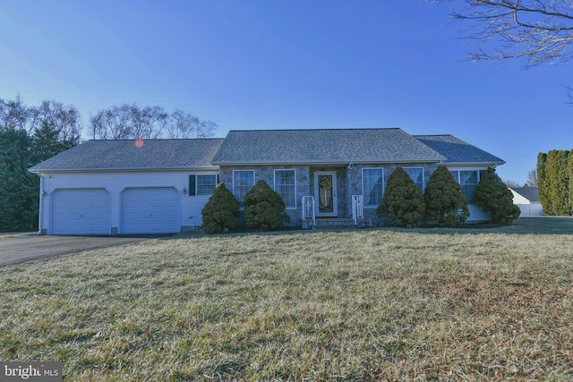 single story home with driveway, an attached garage, and a front yard