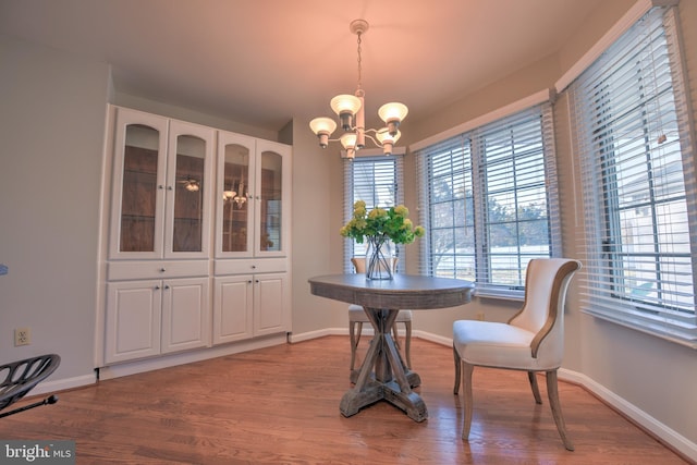 dining space with an inviting chandelier, baseboards, and wood finished floors