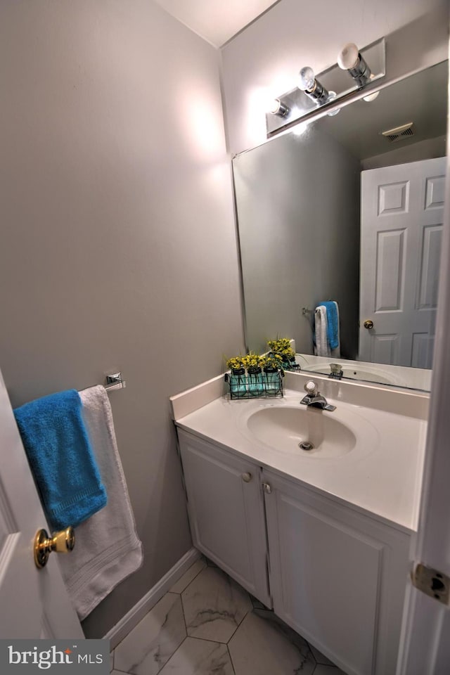 bathroom featuring marble finish floor, vanity, visible vents, and baseboards