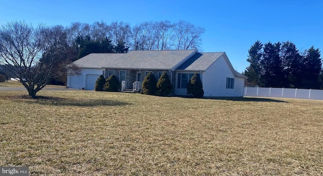 ranch-style house featuring an attached garage, fence, and a front yard