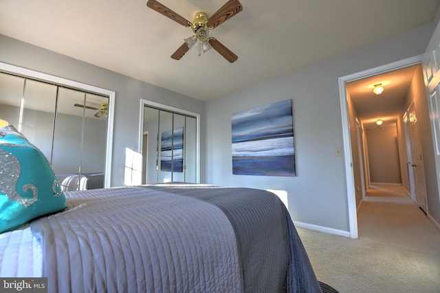 carpeted bedroom with two closets, a ceiling fan, and baseboards