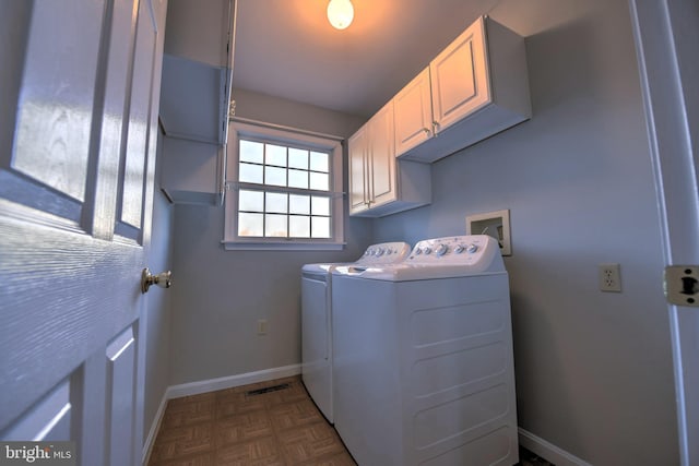 clothes washing area with visible vents, washer and clothes dryer, cabinet space, and baseboards