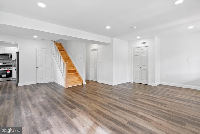 basement with dark wood-type flooring and stainless steel fridge