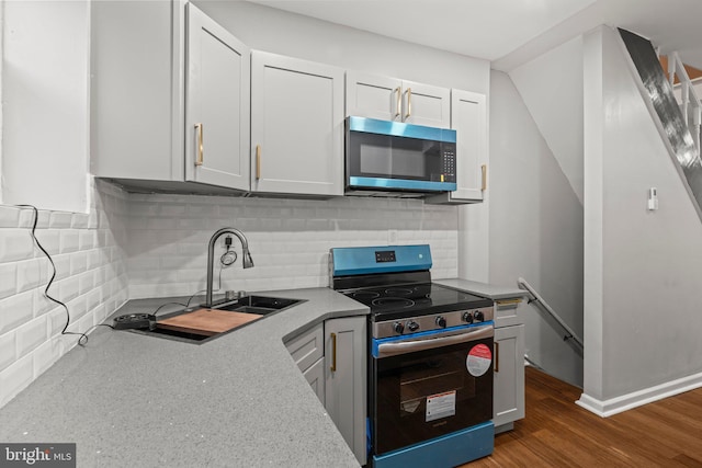 kitchen featuring dark wood-type flooring, stainless steel electric range oven, sink, and decorative backsplash