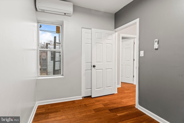 corridor with wood-type flooring and a wall mounted AC