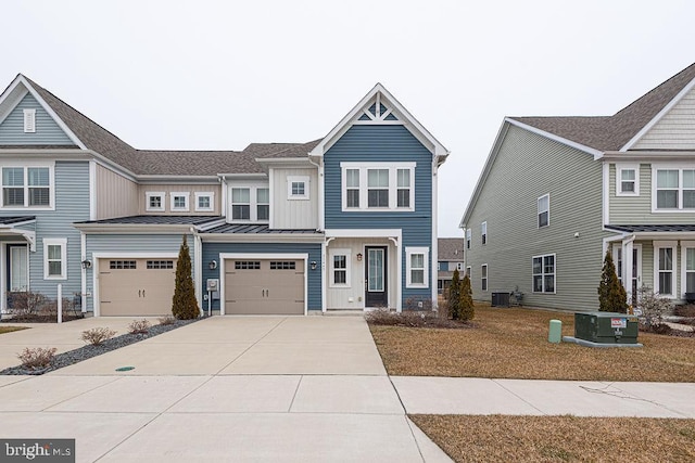 townhome / multi-family property featuring central air condition unit, concrete driveway, board and batten siding, a standing seam roof, and a garage