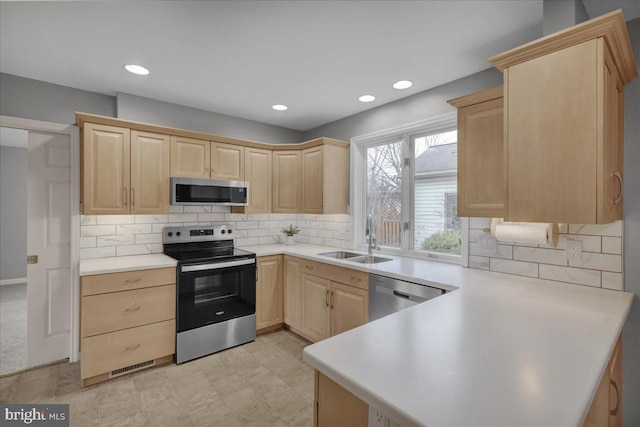 kitchen featuring tasteful backsplash, appliances with stainless steel finishes, light countertops, light brown cabinets, and a sink