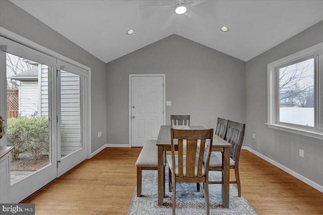 dining room featuring lofted ceiling, baseboards, and light wood finished floors