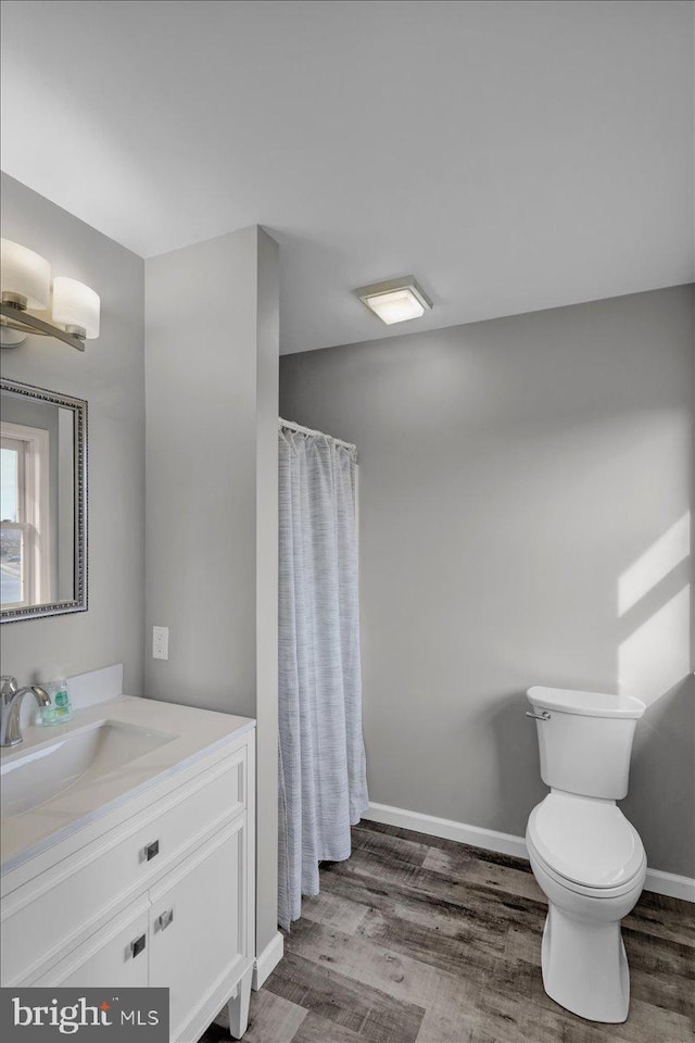 bathroom featuring baseboards, toilet, a shower with curtain, wood finished floors, and vanity