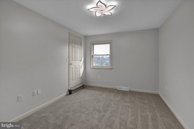 unfurnished room with visible vents, baseboards, and light colored carpet