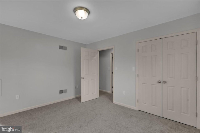 unfurnished bedroom featuring baseboards, visible vents, a closet, and light colored carpet