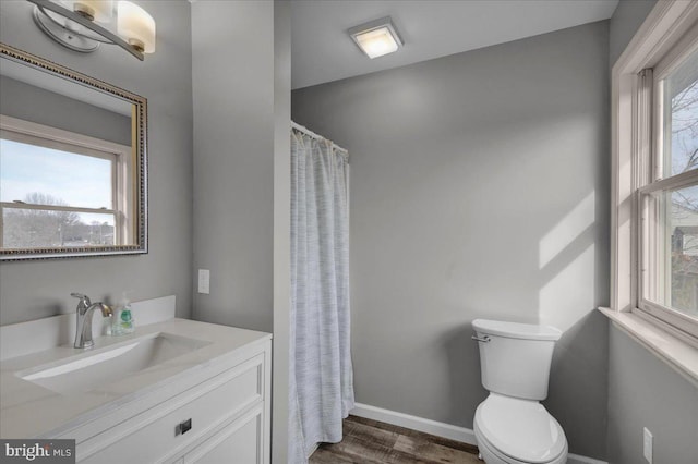 bathroom featuring a healthy amount of sunlight, toilet, wood finished floors, and vanity