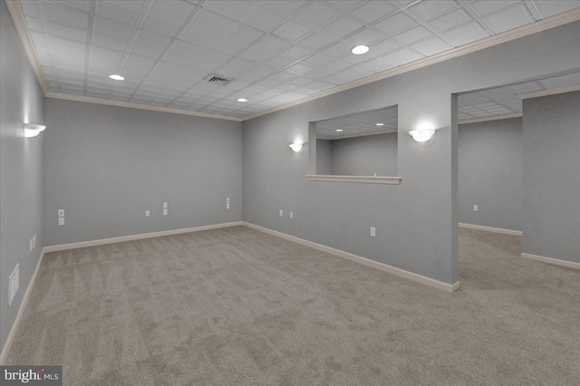 below grade area featuring ornamental molding, carpet, visible vents, and baseboards