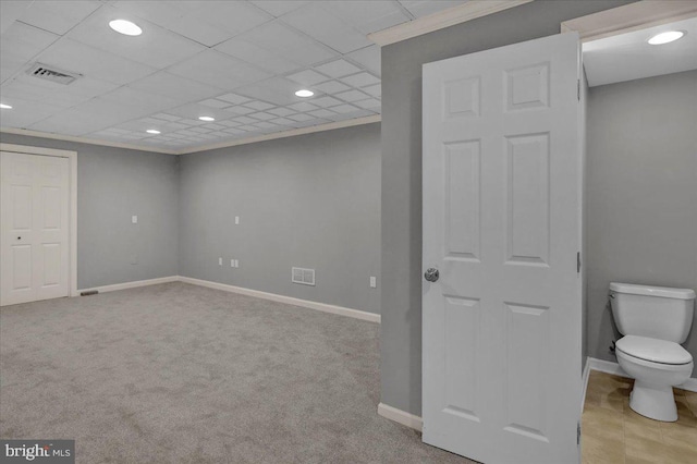 below grade area with light carpet, ornamental molding, visible vents, and baseboards