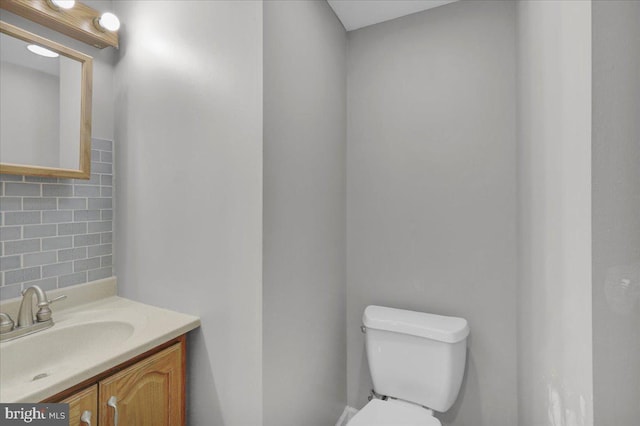 bathroom featuring toilet, vanity, and decorative backsplash