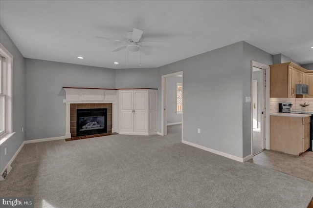 unfurnished living room featuring recessed lighting, light colored carpet, a ceiling fan, a tile fireplace, and baseboards