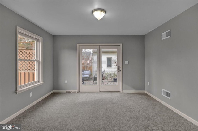 carpeted empty room featuring baseboards and visible vents