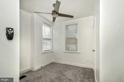 carpeted empty room featuring visible vents, a ceiling fan, and baseboards