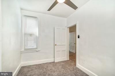 carpeted empty room featuring baseboards and ceiling fan