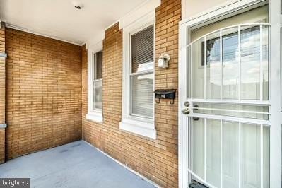 view of exterior entry with brick siding and a porch