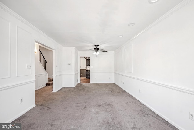 unfurnished living room with carpet flooring, crown molding, stairs, and a decorative wall