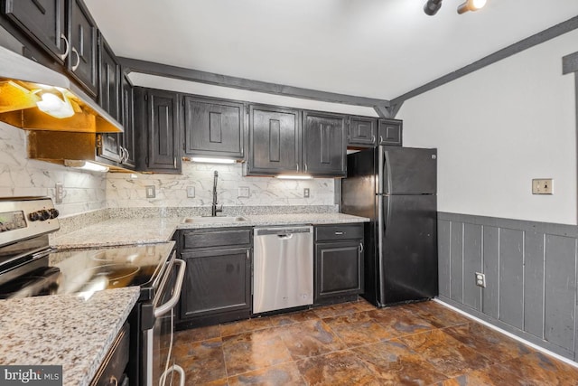 kitchen featuring tasteful backsplash, a wainscoted wall, exhaust hood, stainless steel appliances, and a sink