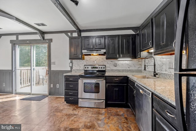 kitchen with under cabinet range hood, wainscoting, appliances with stainless steel finishes, dark cabinetry, and a sink