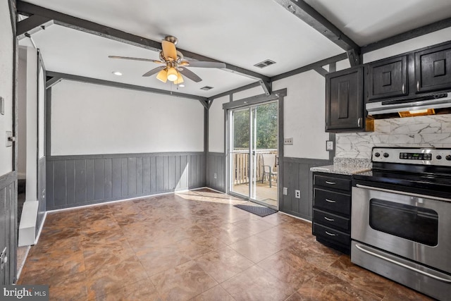 kitchen with beamed ceiling, under cabinet range hood, stainless steel range with electric cooktop, wainscoting, and dark cabinets