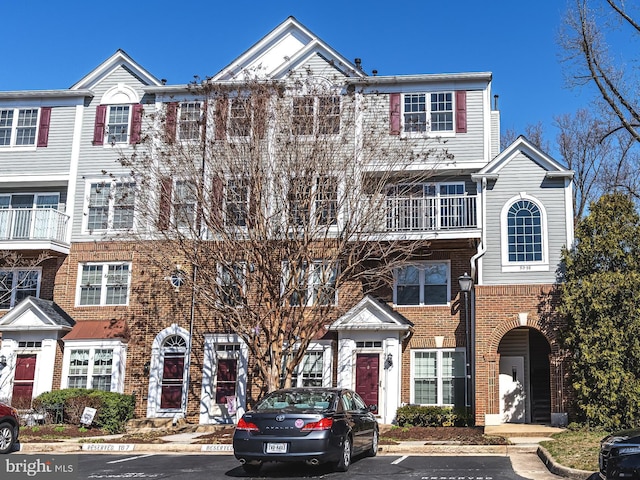 multi unit property with brick siding and uncovered parking