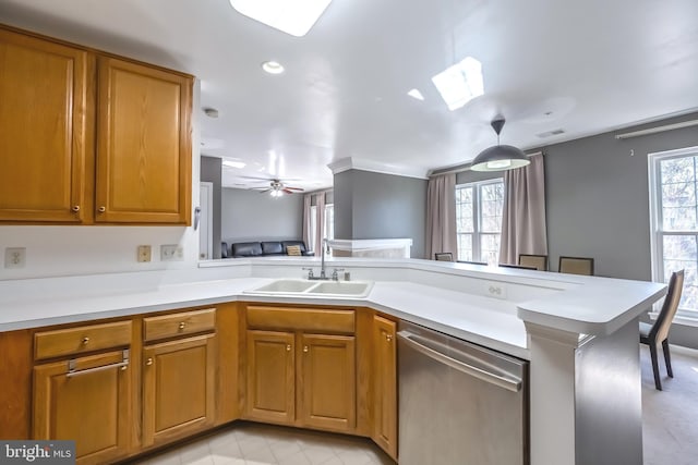 kitchen featuring a sink, stainless steel dishwasher, a peninsula, and a wealth of natural light