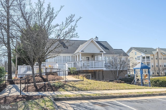view of front of home with playground community, a residential view, covered porch, and fence
