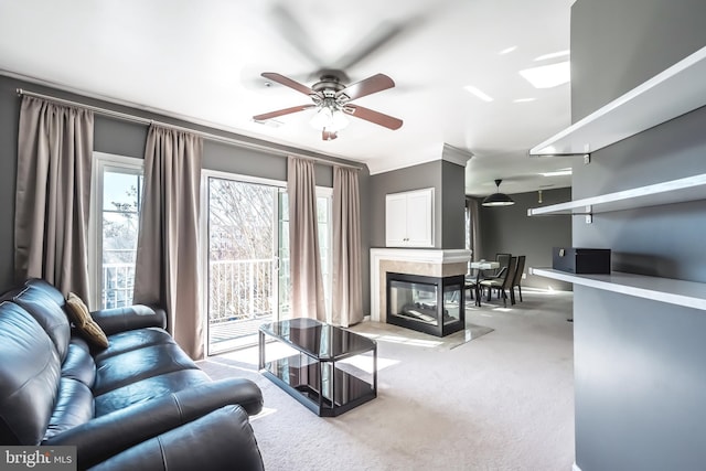 living area with light colored carpet, ceiling fan, and a high end fireplace