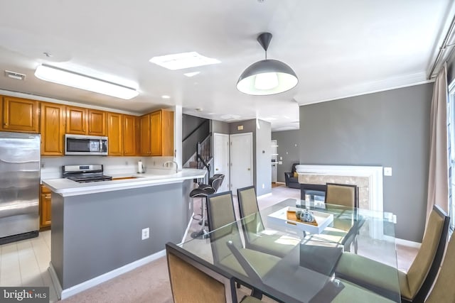 kitchen with brown cabinetry, baseboards, visible vents, a peninsula, and appliances with stainless steel finishes