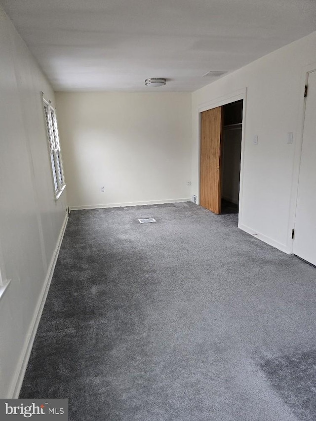 unfurnished bedroom with dark colored carpet, a closet, and baseboards