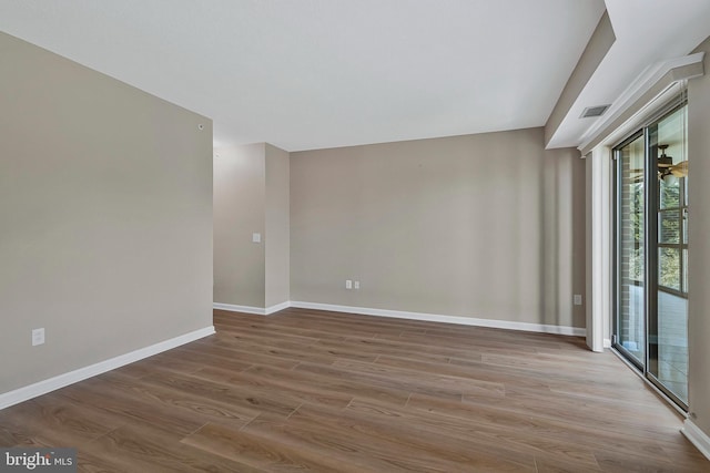 unfurnished room with wood finished floors, visible vents, and baseboards