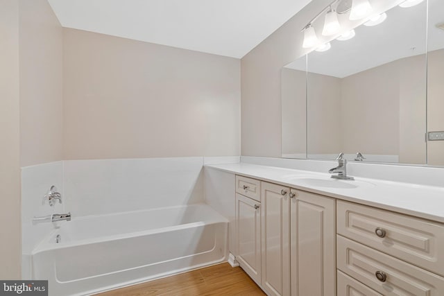 bathroom featuring a garden tub, vanity, and wood finished floors