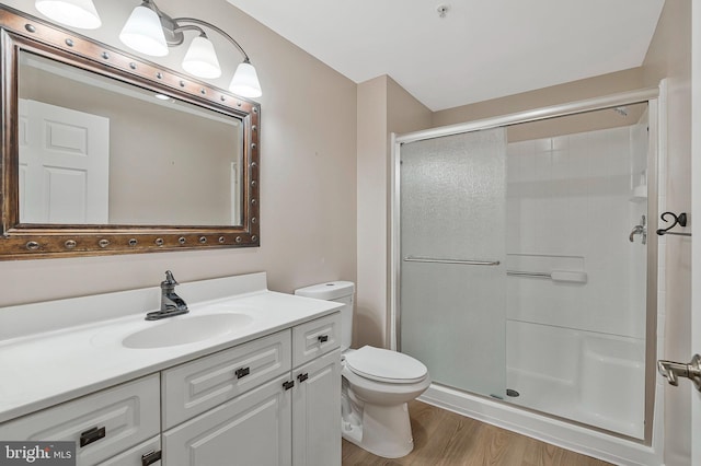 bathroom with vanity, wood finished floors, a shower stall, and toilet