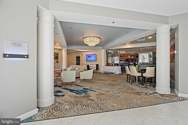 living area with marble finish floor, bar, decorative columns, and baseboards